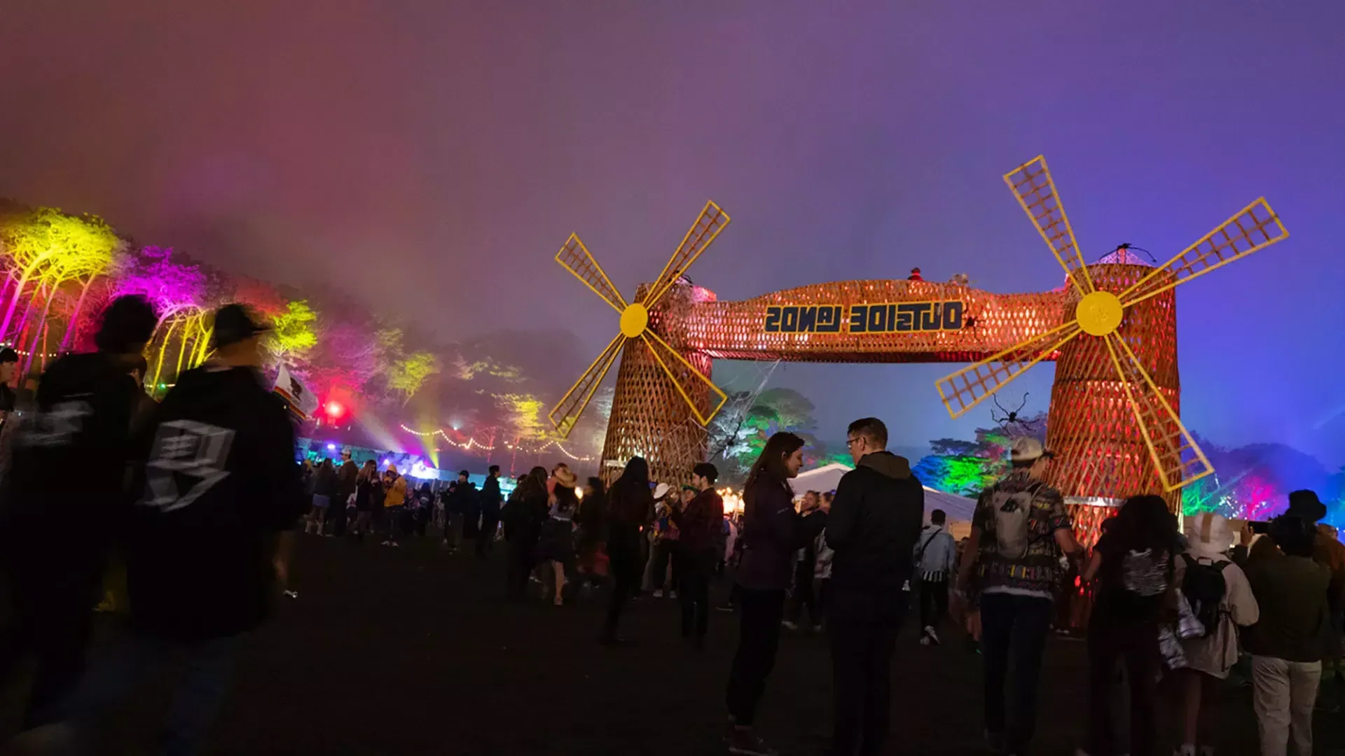 Uma multidão de 节日eiros é fotografada à noite em meio a luzes de néon no 节日 de 音乐 外的土地, 在贝博体彩app.