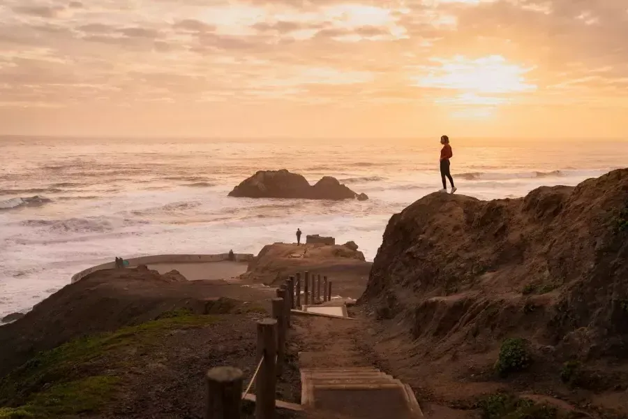 Two people stand on rocks overlooking 的 ocean at 海水浴场 in San Francisco.