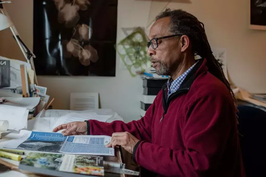 Ron Moultrie Saunders sitting at his desk reading